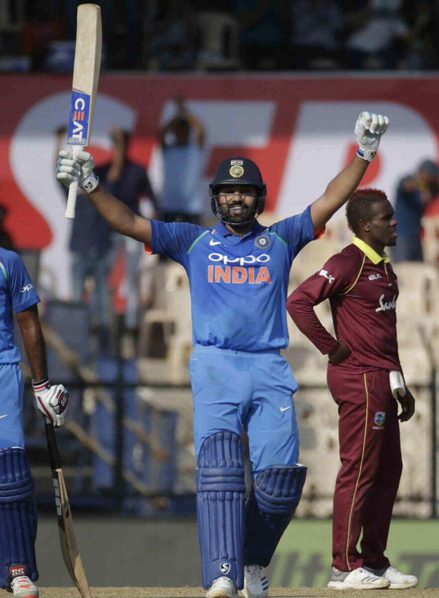 India's Rohit Sharma raises his bat to celebrate scoring a century during the fourth one-day international cricket match between India and West Indies in Mumbai, India, Monday, Oct. 29, 2018.