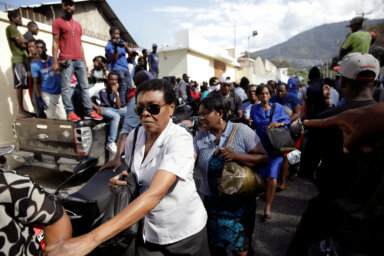 Women walk in line outside of the Haitian Ministry of Justice and Public Security after protesters broke the gate and ask people inside to leave during a protest in Port-au-Prince