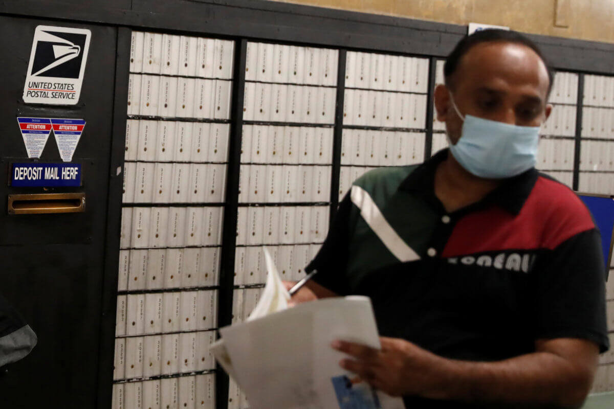 Man wearing a protective mask stands inside USPS office in the Queens borough of New York