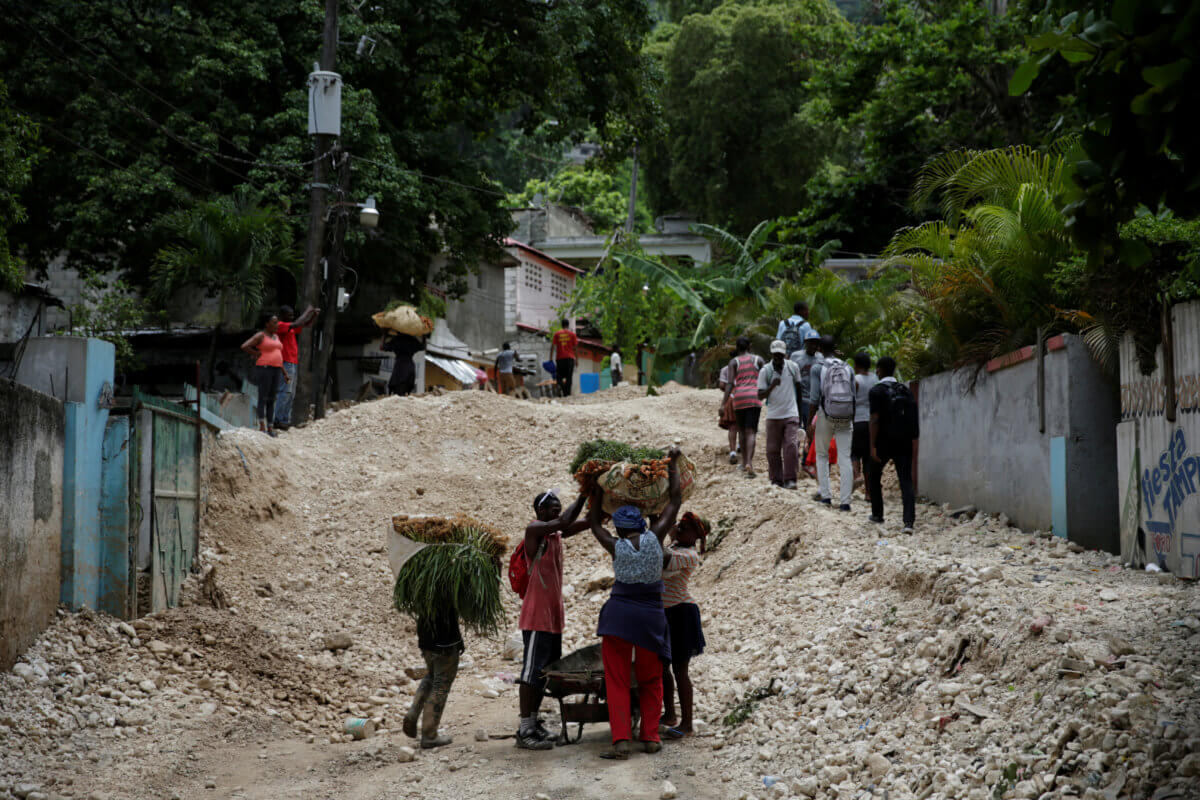 Residents walk along a street affected by the passage of Tropical Storm Laura, in Port-au-Prince