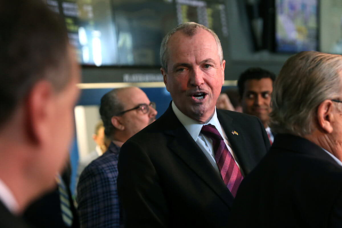 New Jersey Governor Phil Murphy speaks to a colleague before placing the first legal sports bets in the State of New Jersey at Monmouth Park Sports Book by William Hill, in Oceanport