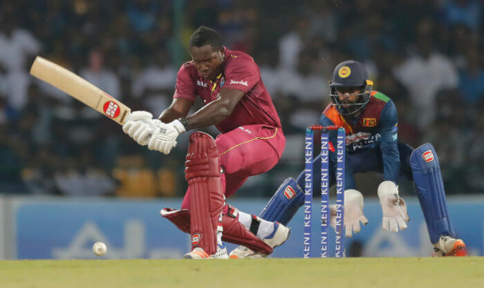 West Indies' batsman Rovman Powell plays a shot as Sri Lanka's wicketkeeper Niroshan Dickwella watches during their second Twenty20 cricket match in Pallekele, Sri Lanka, Friday, March 6, 2020. 