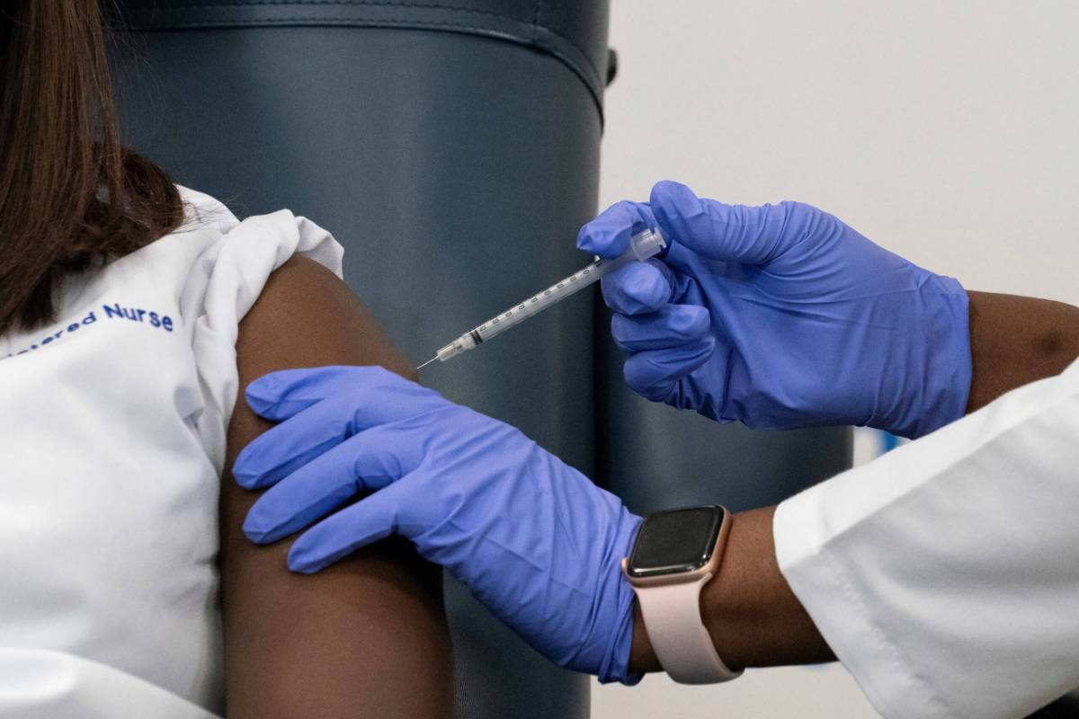 Sandra Lindsay,  a nurse at Long Island Jewish Medical Center, is inoculated with the coronavirus disease (COVID-19) vaccine by Dr. Michelle Chester from Northwell Health at Long Island Jewish Medical Center in New Hyde Park, New York