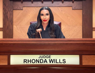 Rhonda Wills – RJ sitting on set behind bench.