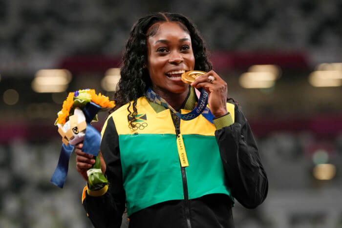 Jamaica's Elaine Thompson-Herah poses with her gold medal after winning women's 100m at the 2020 Summer Olympics, Sunday, Aug. 1, 2021, in Tokyo, Japan.