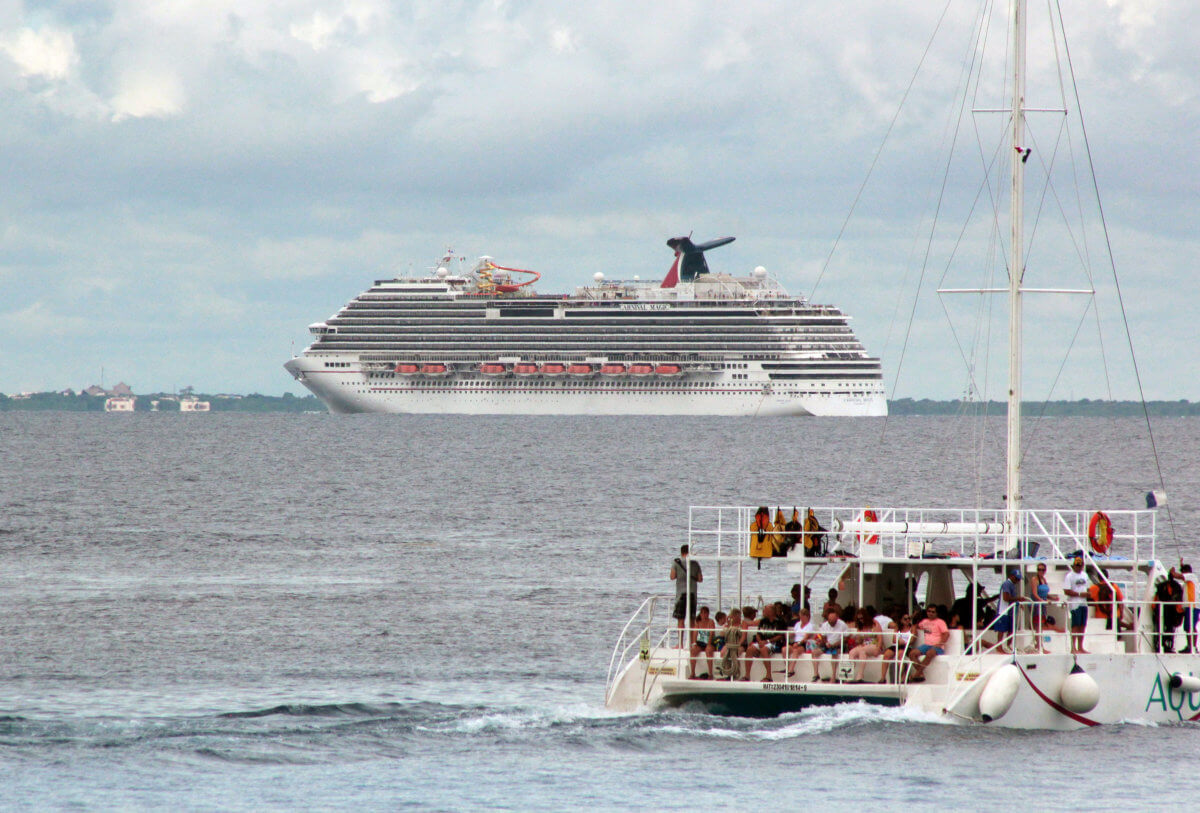 FILE PHOTO: Tourists enjoy a ride on a catamaran as cruise ship Carnival Magic is seen near the shores of Cozumel