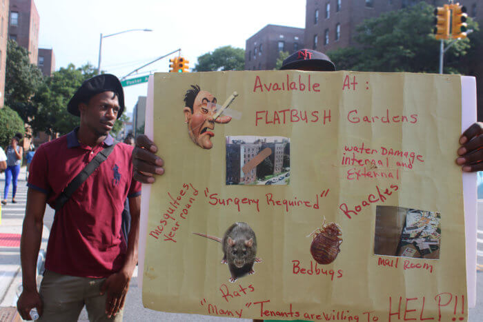 A placard shows the unhealthy conditions residents of Flatbush Gardens have to live in