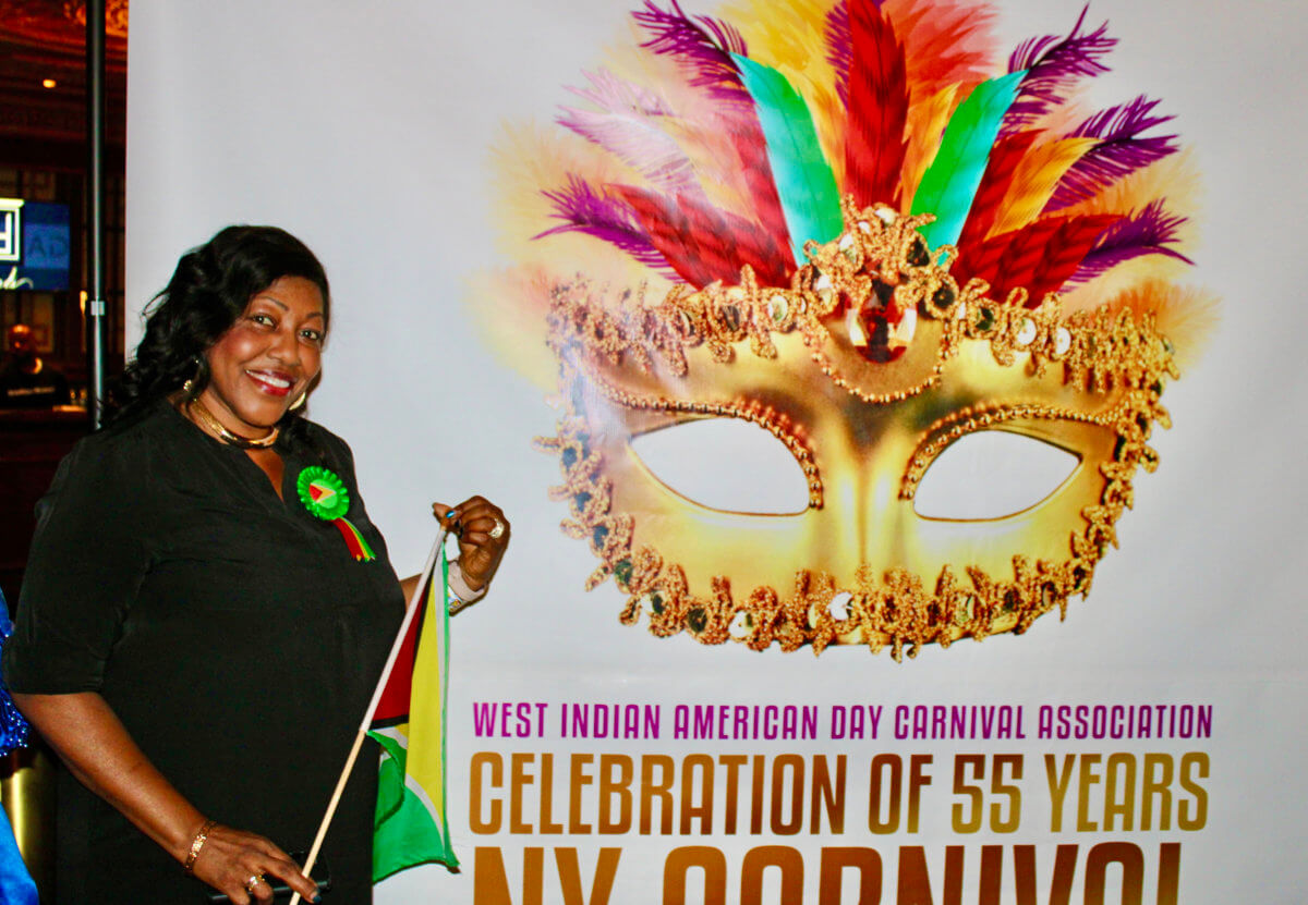 Guyanese American Sherif Barker, newest committee member of WIADCA, poses with Guyana's Golden Arrowhead flag against the 2022 Carnival backdrop, at the recent kick-off at Kings Theatre, on Flatbush Avenue in Brooklyn.