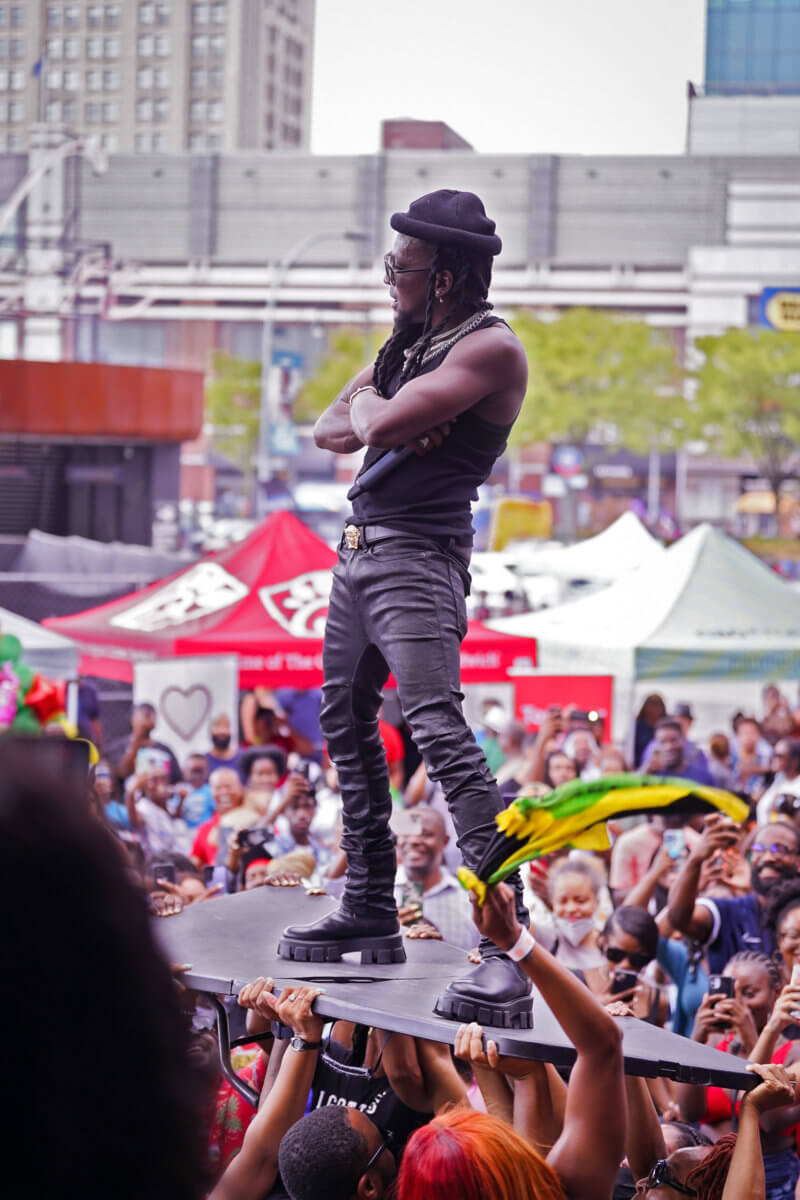 Mr. Killa stands on a table while being held up by fans.