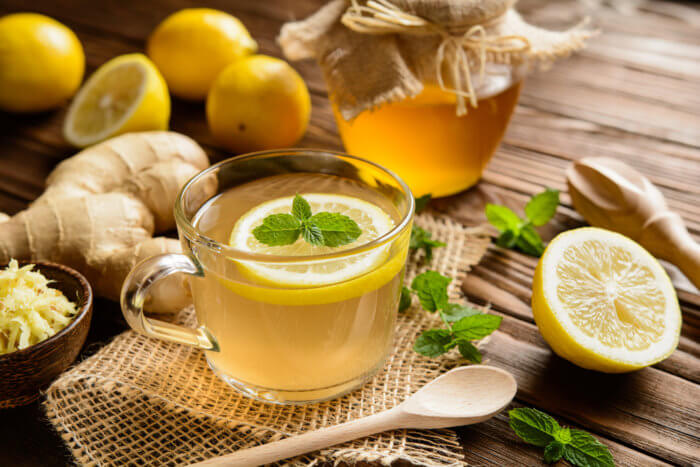 Cup of ginger root tea with lemon, honey and mint on a wooden background. 