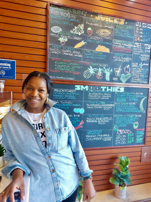 Abigail Caesar, owner of Canarsie Blend Juice bar, against the backdrop of the menu of juices and smoothies at the Brooklyn business.