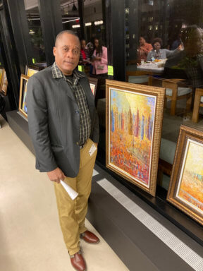 Haitian artist Jean Eddy Beauvoir stands in front of his work.