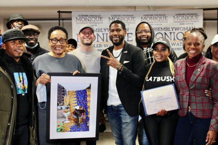 A supporter, with Marietta Small, holding a picture of late actor, Michael K. Williams, Public Advocate Jumaane Williams, Dr. Meda Leacock, and Assemblywoman Monique Chandler Waterman, during the 13th Annual Thanksgiving Turkey Giveaway, at Flatbush Gardens, Brooklyn.