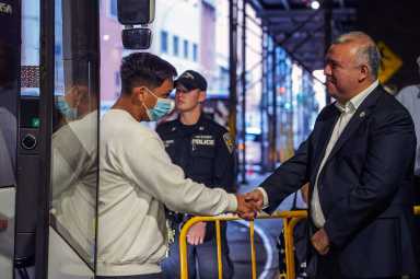 Mayor’s Office of Immigrant Affairs Commissioner Manuel Castro shakes hands as migrants step off the bus.