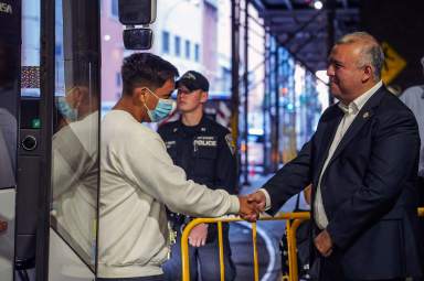 Mayor’s Office of Immigrant Affairs Commissioner Manuel Castro shakes hands as migrants step off the bus.