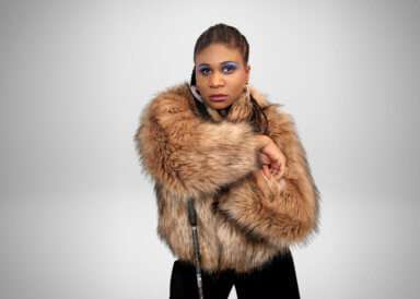 RAMPD Founder Lachi, who is a black and blind seen here wearing a brown fur coat, and holding her black, glittery identification cane. 