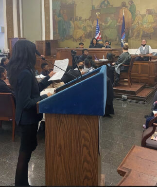 Harlem Village Academy student attorney questioning a witness during a mock trial organized by Justice Machelle Sweeting.