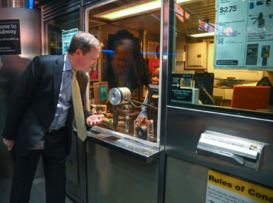 MTA NYC Transit President Richard Davey chats with a subway station agent behind a booth at Fulton Street.