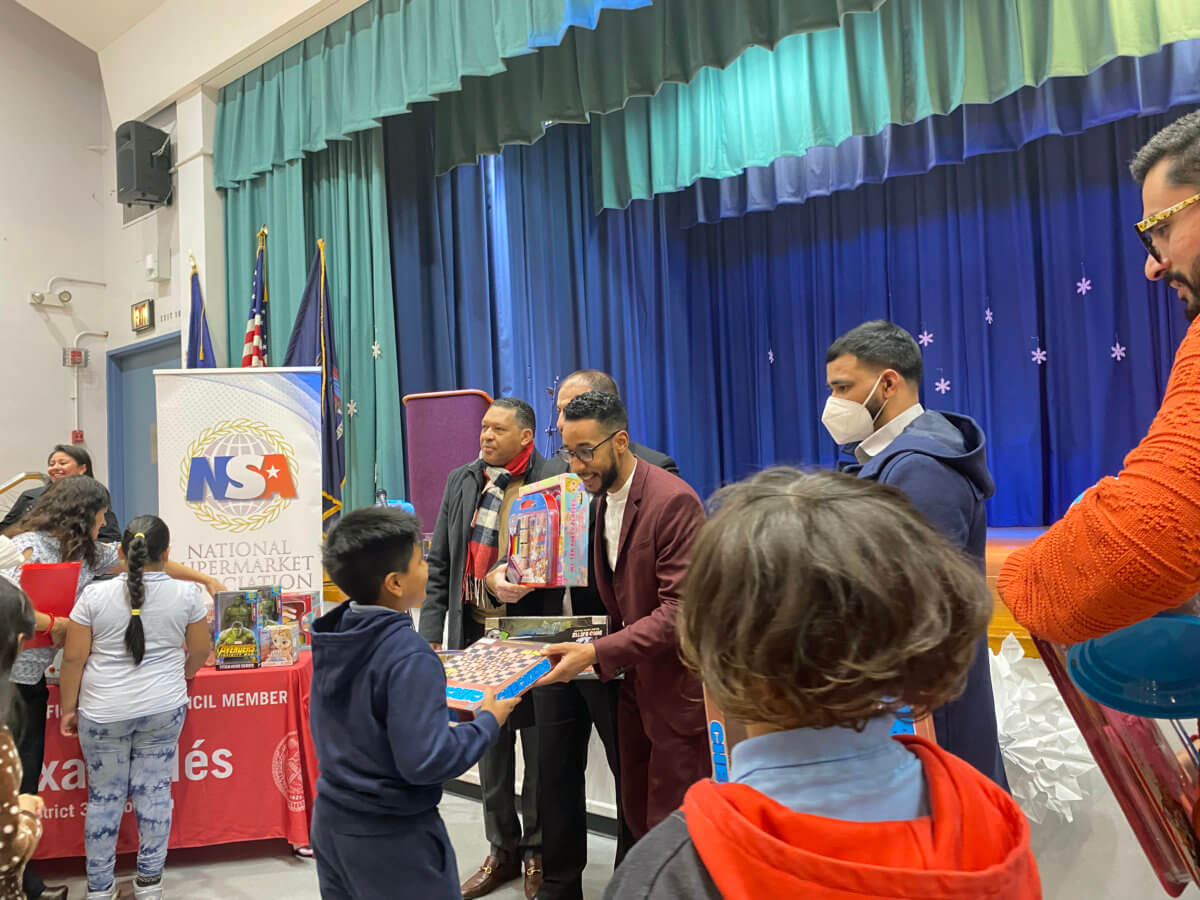 Brooklyn Borough President Antonio Reynoso, hands over a toy to a student at Three Kings Day celebration.