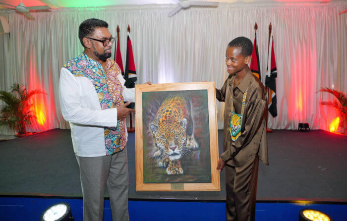 President Irfaan Ali presents Black Panther star, Letitia Wright with a picture of Guyana's national animal, the Jaguar at State House, during her visit to her homeland, after leaving at age eight.
