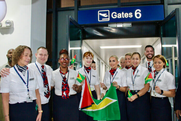 British Airways flight attendants wave the Golden Arrowhead flag after disembarking the 777-200ER aircraft at Cheddi Jagan Int. Airport for a photo-op.
