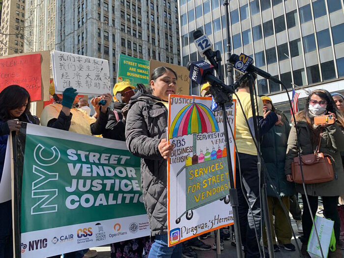 Vendors protest with various signs in a line around City Hall.