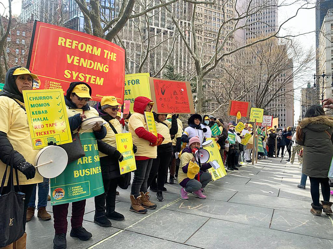 Vendors in a line around City Hall with signs in six languages reading “Cut the Red Tape” and “Street Vendors are Small Businesses.”