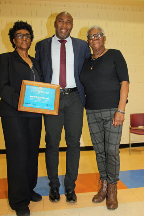 Minister Dr. Orando L. Brewster with SVG Relief USA, Inc. Chair, Verna Arthur, left, with plaque, and Vice Chair, Celia Bramble.