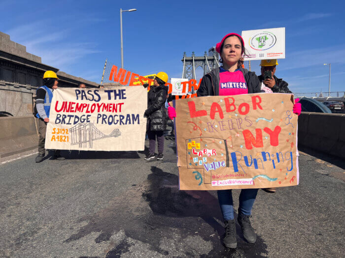 Excluded workers hold signs calling for the Unemployment Bridge Program.