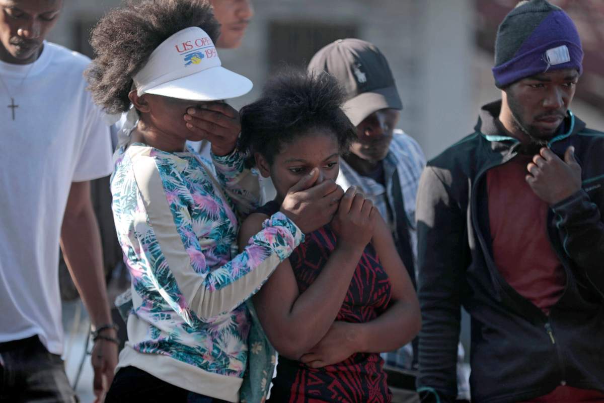 Bystanders look at the bodies of alleged gang members that were set on fire by a mob after they were stopped by police while traveling in a vehicle in the Canape Vert area of Port-au-Prince, Haiti, Monday, April 24, 2023.