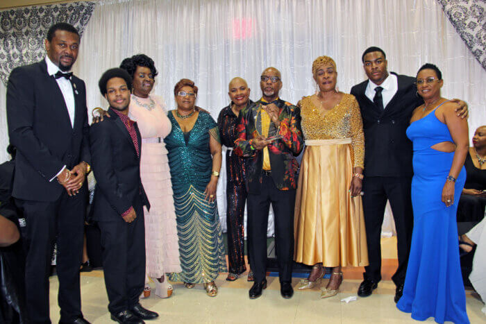 Osborne "Sheen" Millington, with plaque, flanked by family members, and Consul General Rondy "Luta" McIntosh (far left) his wife, Semone (far right).