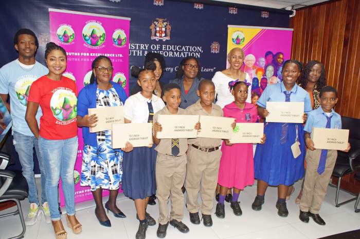 Jénine Shepherd, founder, board chair and president of Youths for Excellence Limited extreme left second row, with students, and other officials after the electronic tablets were handed over.
