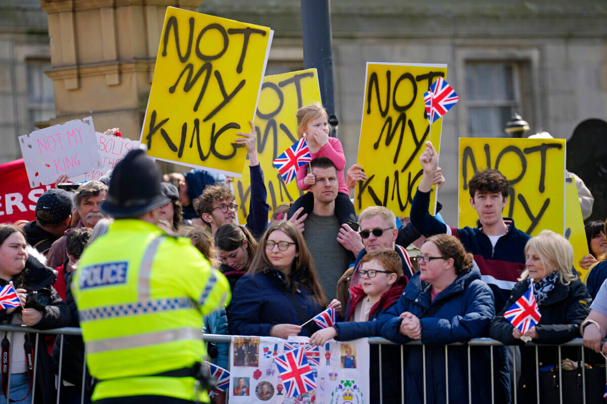 FILE - Protestors wait for the arrival of King Charles III and Camilla, the Queen Consort to visit Liverpool Central Library, and to officially mark the Library's twinning with Ukraine's first public Library, the Regional Scientific Library in Odesa, in Liverpool, England, Wednesday, April 26, 2023.