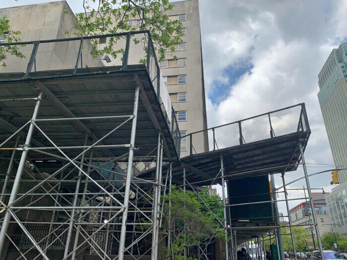The scaffolding encircles the entire building — around the front at Columbus Park, down both sides, and along Adams Street. 