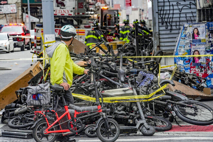 FILE - A biker stops to look at a pile of e-bikes in the aftermath of a fire in Chinatown, which authorities say started at an e-bike shop and spread to upper-floor apartments, Tuesday, June 20, 2023, in New York. New York City is receiving $25 million in emergency funding from the U.S. Department of Transportation to establish scores of new e-bike charging stations across the city. Mayor Eric Adams announced the funding Sunday, June 25.