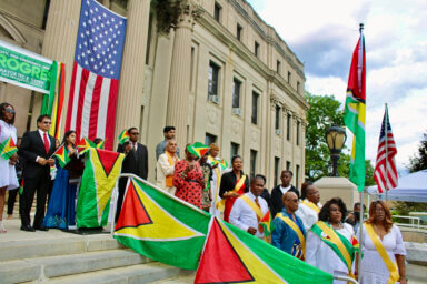 Guyanese stood for the National Anthem after the Golden Arrowhead Flag was hoisted by Lady Ira Lewis and the Guyana America Heritage Foundation members at the foot of the steps of East Orange City Hall, NJ.