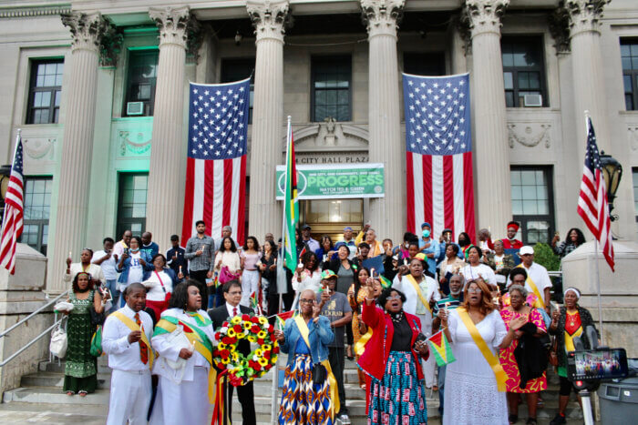 Expatriates during a symbolic candlelight and wreath ceremony on the steps of East Orange City Hall to mourn the loss 20 children who perished in a fire in Mahdia, Guyana.