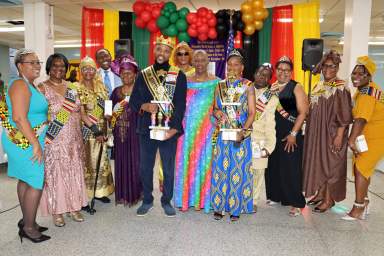IOUM community liaison Hyacinth-Robinson-Goldson, center, with the Jamaican Wayne A. Wiles (King) and Barbadian Betty Thorpe (Queen) and contestants.