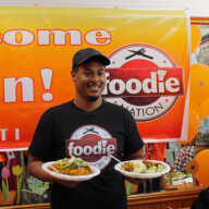Trinbagonian foodie nation chef Shaun, who has thousands of followers on social media, holding plates of delicious Chicken Pelau, cucumber salad, and potato salad, prepared in Chicken Curry Box the kitchen to promote ALLFROM1SUPPLIER.COM  a Caribbean cooked food and groceries shipping platform.