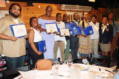 New inductees with certificates, flanked by President Jean Joseph, second from right, and Lion Past District Gov. Trinidadian Jackie Phillips, right.