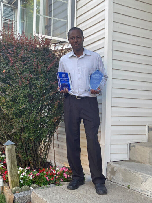 Hilton Samuel outside of his home, with two of his lifetime achievement awards.
