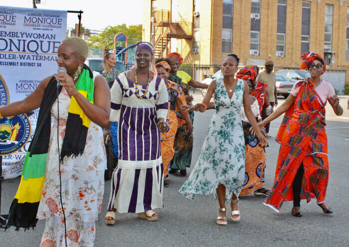 From left, singer Ellan Neil, and Assemblywoman Monique Chandler-Waterman, third from left join dancers on the Holy Family Church grounds during the first Folk Festival in the community.