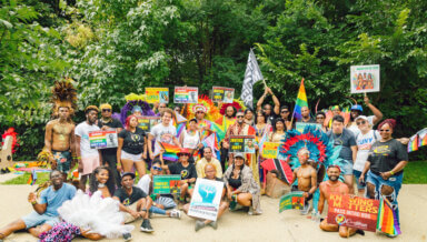 Mohamed Q. Amin, founder and executive director of the Caribbean Equality Project, seventh from left front, standing, with "Justice for Jonty" sign, surrounded by a contingent after participating in the WIADCA parade on Eastern Parkway, Sept. 4.