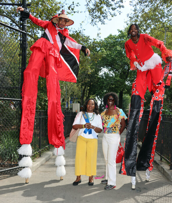 Corporation Counsel Barbadian Sylvia Hinds-Radix, left, with Retired Trinidadian Justice Sylvia G. Ash, of Grenadian and Vincentian parentage, with Stilt Dancers.