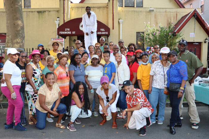 Church members with stilt dancer, at back, in front of Fenimore Street United Methodist Church.