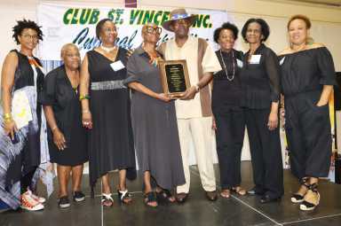 Cyril "Scorcher" Thomas receives award from Exposition Coordinator Verna Arthur, fourth from left, flanked by members of Club St. Vincent, Inc.