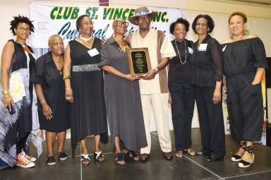 Cyril "Scorcher" Thomas receives award from Exposition Coordinator Verna Arthur, fourth from left, flanked by members of Club St. Vincent, Inc.