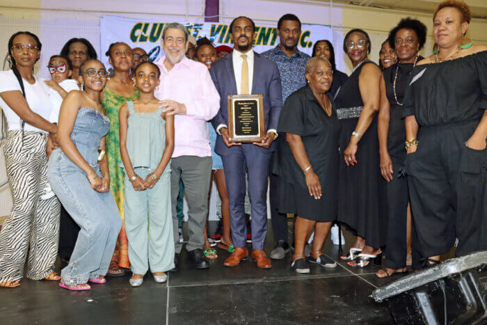 Jabari Edwards with plaque, flanked by PM Dr. Ralph E. Gonsalves, to his immediate right; Consul General Rondy "Luta" McIntosh, to his left; and family members and members of Club St. Vincent, Inc.