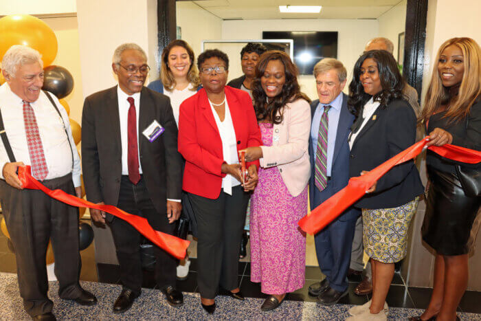 Jean Joseph, center, in red blazer, cuts ribbon to open her new tax consultancy services.
