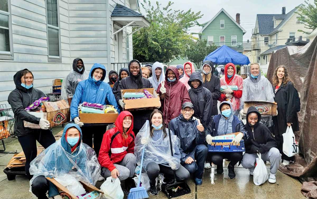 Some of the members of the St. John's University "Red Storm" Women’s Track & Field team, pose with Head Coach Guyanese-born, Aliann Pompey, standing in second row, fourth from left (fingers in peace sign), in front of long time friend and colleague, Roger Gary (fourth from left stooping).